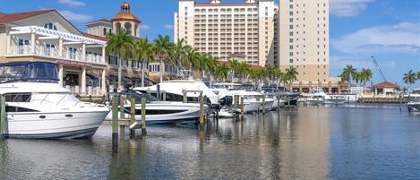 A marina with boats docked, a hotel named 'Westin' in the background, and a building with a dome and palm trees in the foreground.