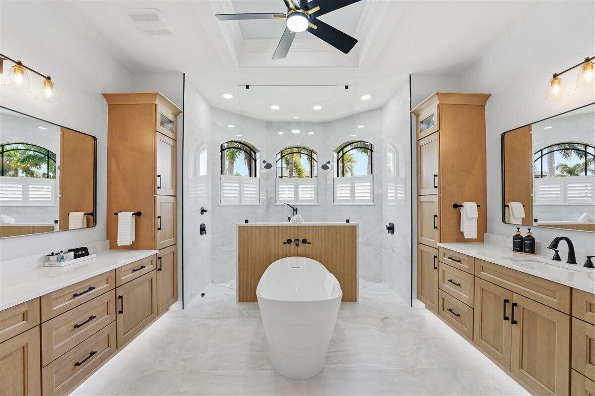 A modern bathroom with a freestanding bathtub, wooden cabinets, and large mirrors.