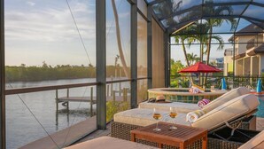 A covered outdoor area with a pool, lounge chairs, and a view of the water. - 90Degree Heated Pool/Spa - Nature Preserve SW Spreader Views (Cape Coral)