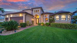 A residential house with a well-maintained lawn, a garage, and a driveway. - 90Degree Heated Pool/Spa - Nature Preserve SW Spreader Views (Cape Coral)