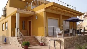 A two-story building with a covered patio, outdoor seating, and a staircase leading to the entrance. - Luxury villa in la manga (Playa Honda)