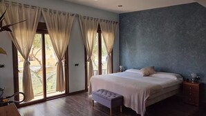 A bedroom with a bed, bench, nightstand, and large windows with curtains. - Luxury villa in la manga (Playa Honda)