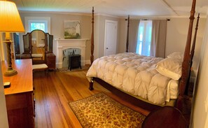 A bedroom with a four-poster bed, a fireplace, a wooden dresser, and a lamp. - Historic, private 3-bedroom house in Winston-Salem with ample parking. (Winston-Salem)