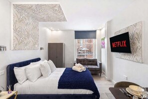 Une chambre d’hôtel moderne dotée d’un grand lit, d’un canapé, d’une télévision et offrant une vue sur la ville.