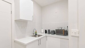 Een kleine kitchenette met een spoelbak, een magnetron en een broodrooster.
