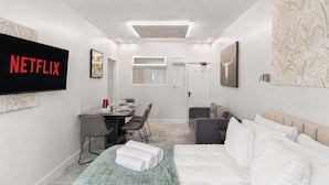 Een moderne hotelkamer met een bed, een bureau, een stoel, een televisie en een deur.