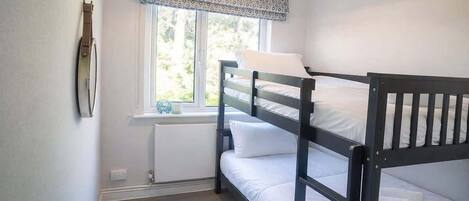 A bunk bed room with a window, radiator, and a hanging light fixture.