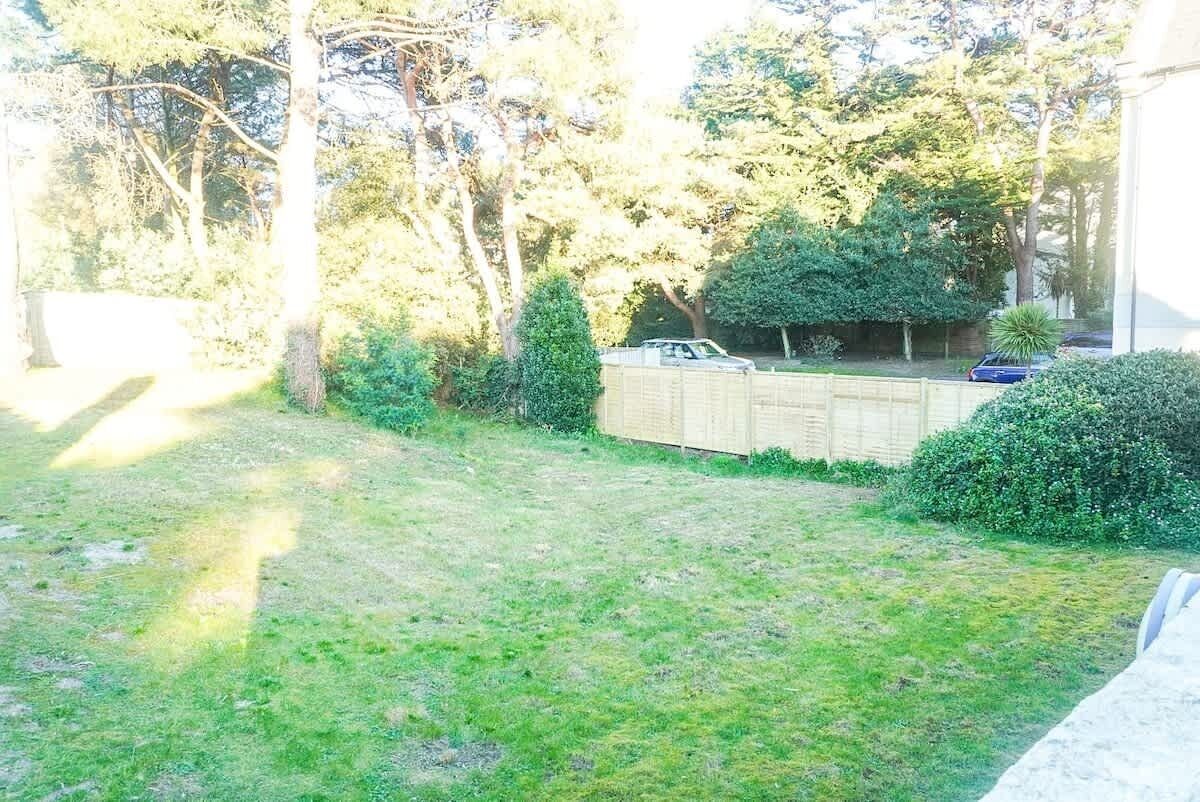 Un jardin avec une clôture en bois, une pelouse et des arbres.
