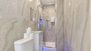 Een moderne badkamer met een douchecabine van glas, een toilet en een wastafel.