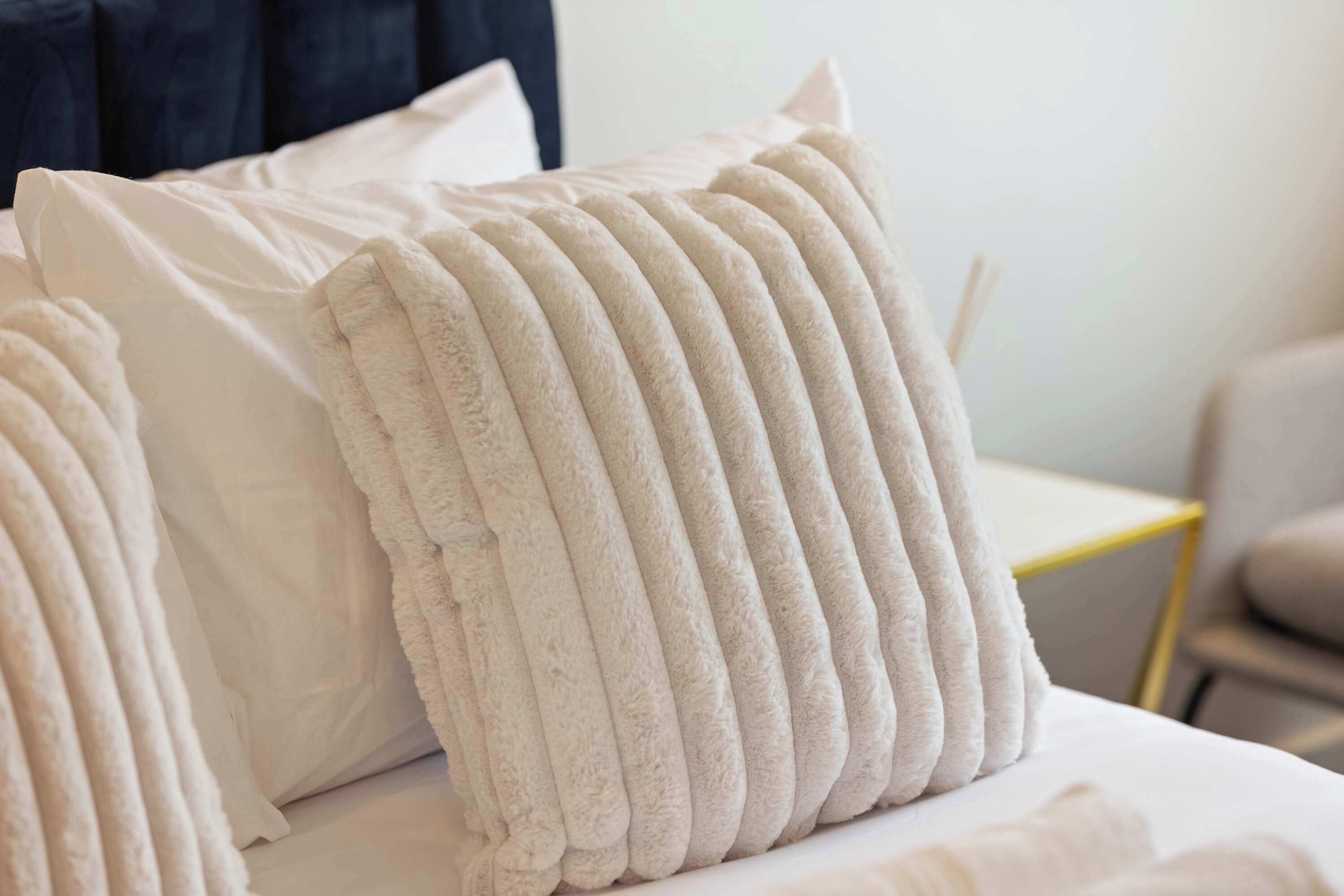 Ein Bett mit weißer Decke und einem strukturierten, gerippten Kopfkissen.