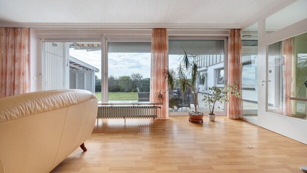 A modern room with a large window, a radiator, a sofa, and potted plants. - Holiday Home for 6 Guests, 150 m², in Winsen (Luhe) with Wi-Fi (Winsen (Luhe))