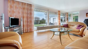 A modern living room with a glass coffee table, leather sofa, and a flat-screen TV. - Holiday Home for 6 Guests, 150 m², in Winsen (Luhe) with Wi-Fi (Winsen (Luhe))