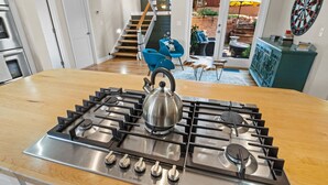 Et køkken med en gasblus fra Bosch i rustfrit stål, en elkedel og en blå stol.