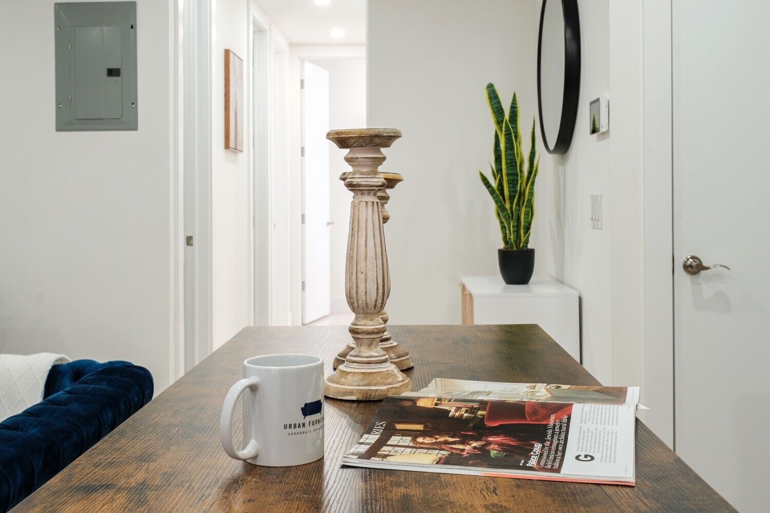 A wooden table with a white mug, a decorative candle holder, and a magazine.