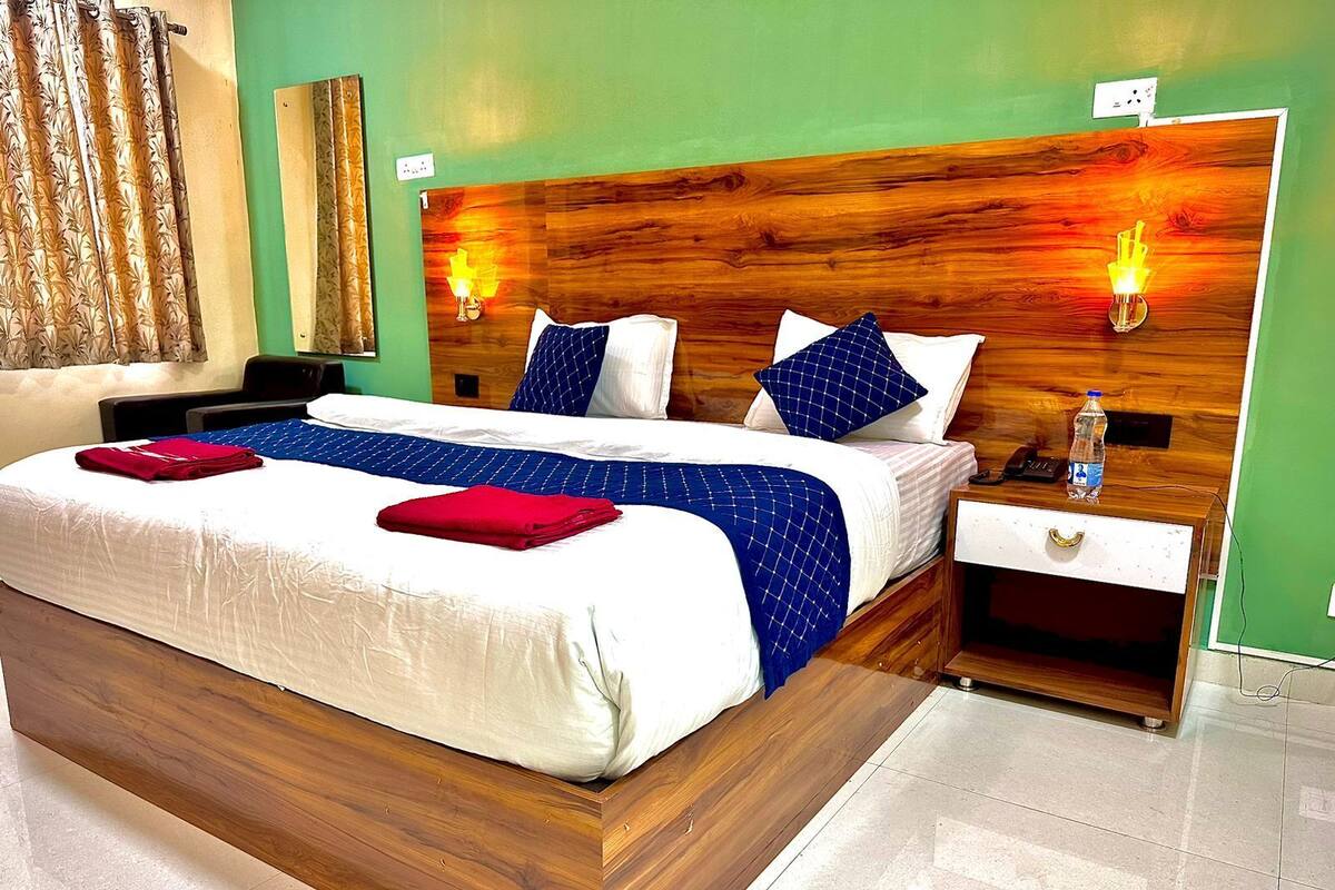 Ein Hotelzimmer mit einem großen Bett, zwei Nachttischen, einem Holz-Kopfteil und zwei Wandleuchten.