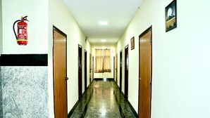 Un pasillo con puertas a ambos lados, un extintor en la pared y un cuadro enmarcado.
