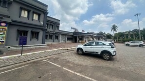 Un edificio con un cartel que indica habitaciones en la planta baja y un coche blanco estacionado frente a él.