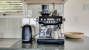 Een koffiezetapparaat, een waterkoker en een gevlochten mand op een aanrecht.