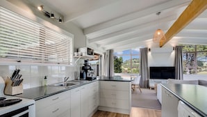Een moderne keuken met witte kastjes, een ingebouwde kookplaat en een groot raam met uitzicht op een schilderachtig landschap.