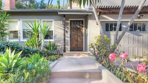 A residential house with a front entrance, steps leading to the door, and a variety of plants and flowers around the entrance. - Beautifully Updated Designer Home near Universal Studios in the Hollywood Hills (Los Angeles)