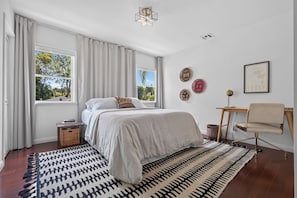 Ein Schlafzimmer mit einem Bett, einem Sessel, einem kleinen Tisch und einem Fenster.