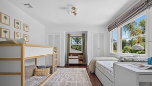 A bedroom with a bunk bed, a desk with a lamp, a window with curtains, and framed botanical prints on the wall. - Beautifully Updated Designer Home near Universal Studios in the Hollywood Hills (Los Angeles)