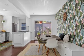 Eine moderne Küche mit weißen Schränken, einem Essbereich mit Tisch und Stühlen sowie einer Wand mit Muster.