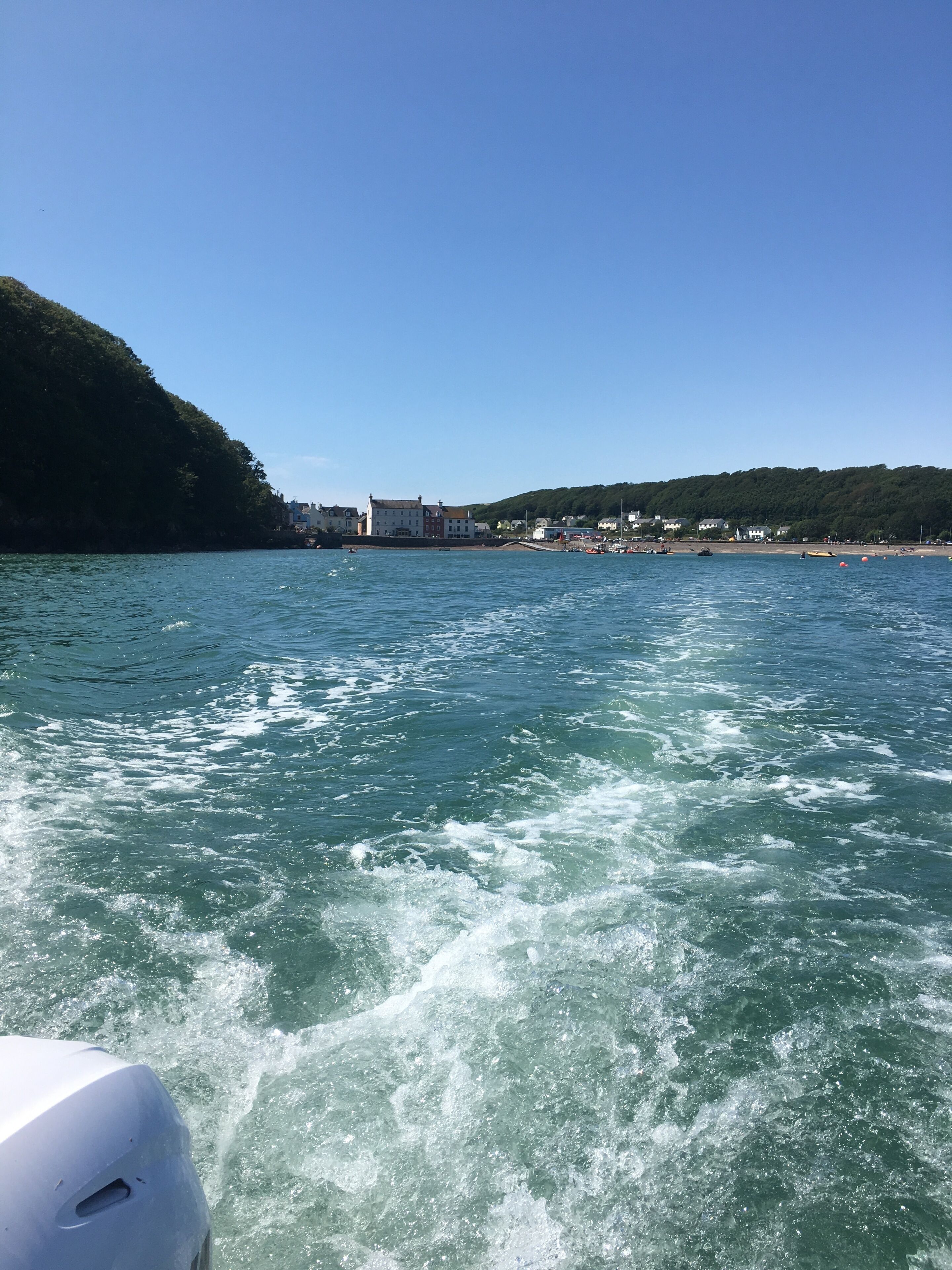 A coastal town with buildings along the shore, a clear sky, and choppy water.