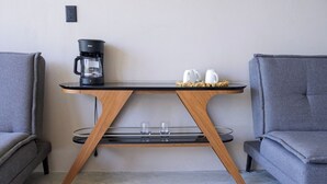 Una mesa moderna con una cafetera, dos tazas y un juego de vasos.