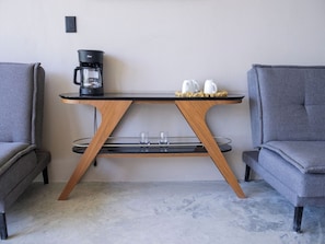 Ein moderner Tisch mit Kaffeemaschine, zwei Tassen und einem Glas-Set.