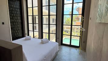 Ein Schlafzimmer mit einem großen Bett, einem Deckenventilator und Blick auf einen Pool sowie Gebäude im Freien.