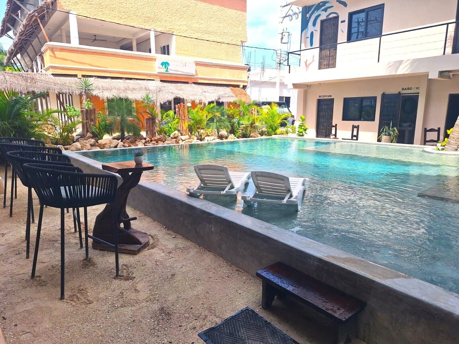 Una piscina con sillones de descanso y una zona de recepción.
