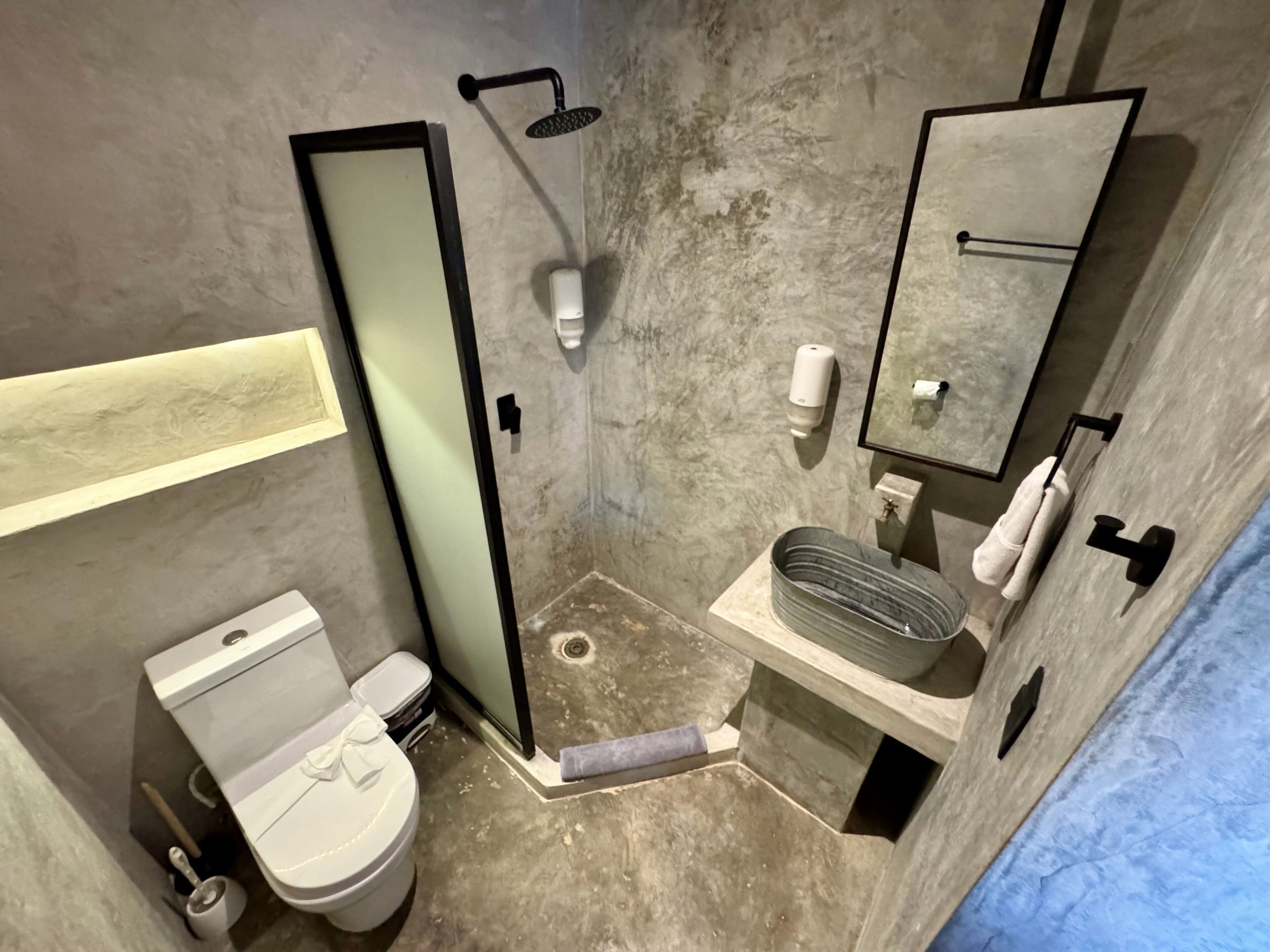Un baño pequeño con inodoro, ducha, lavabo y espejo.