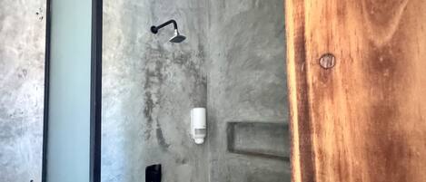 Un baño con ducha, secamanos y dispensador de jabón en la pared.