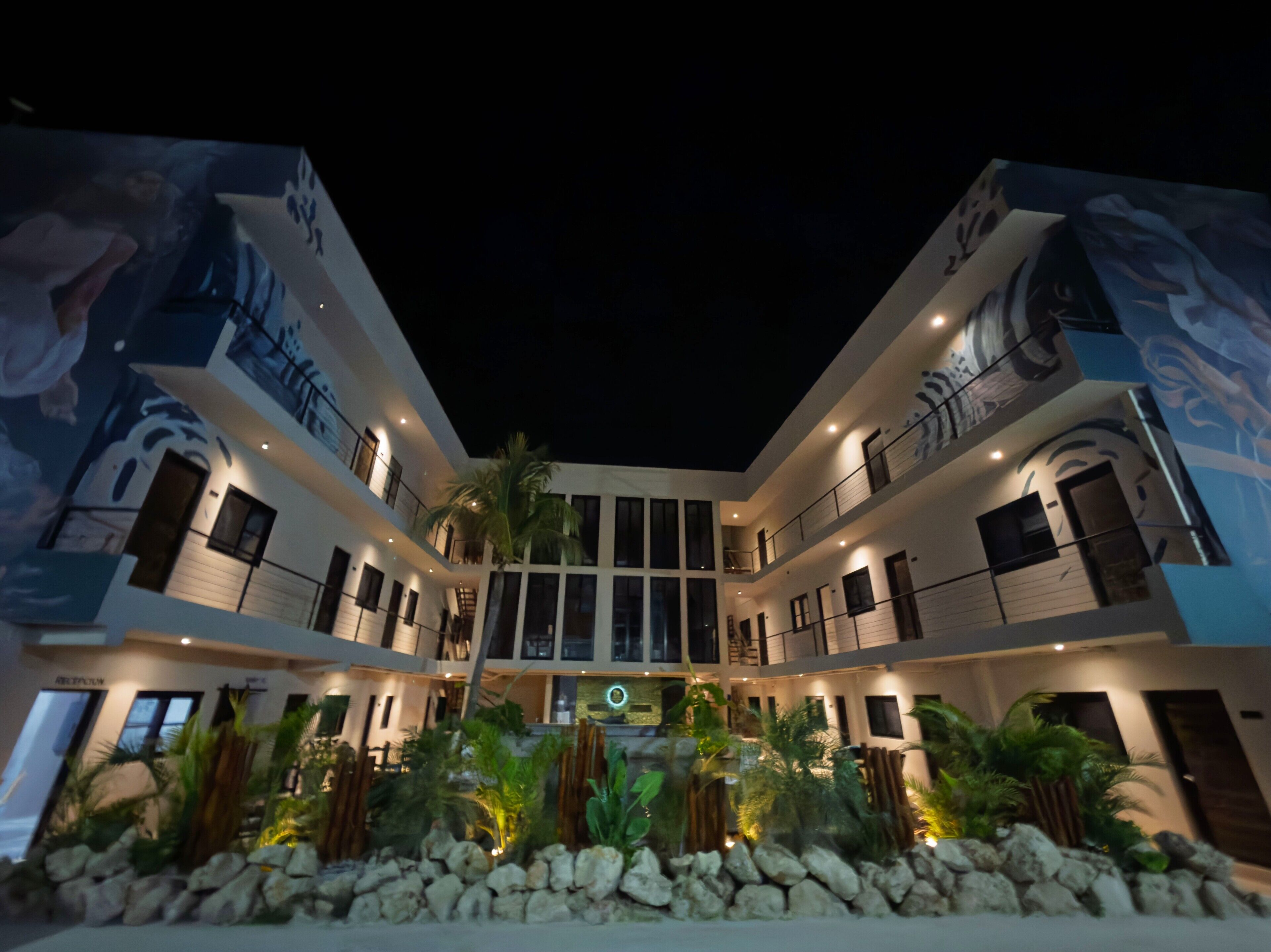 A multi-story hotel with a central atrium, balconies, and a landscaped garden area.