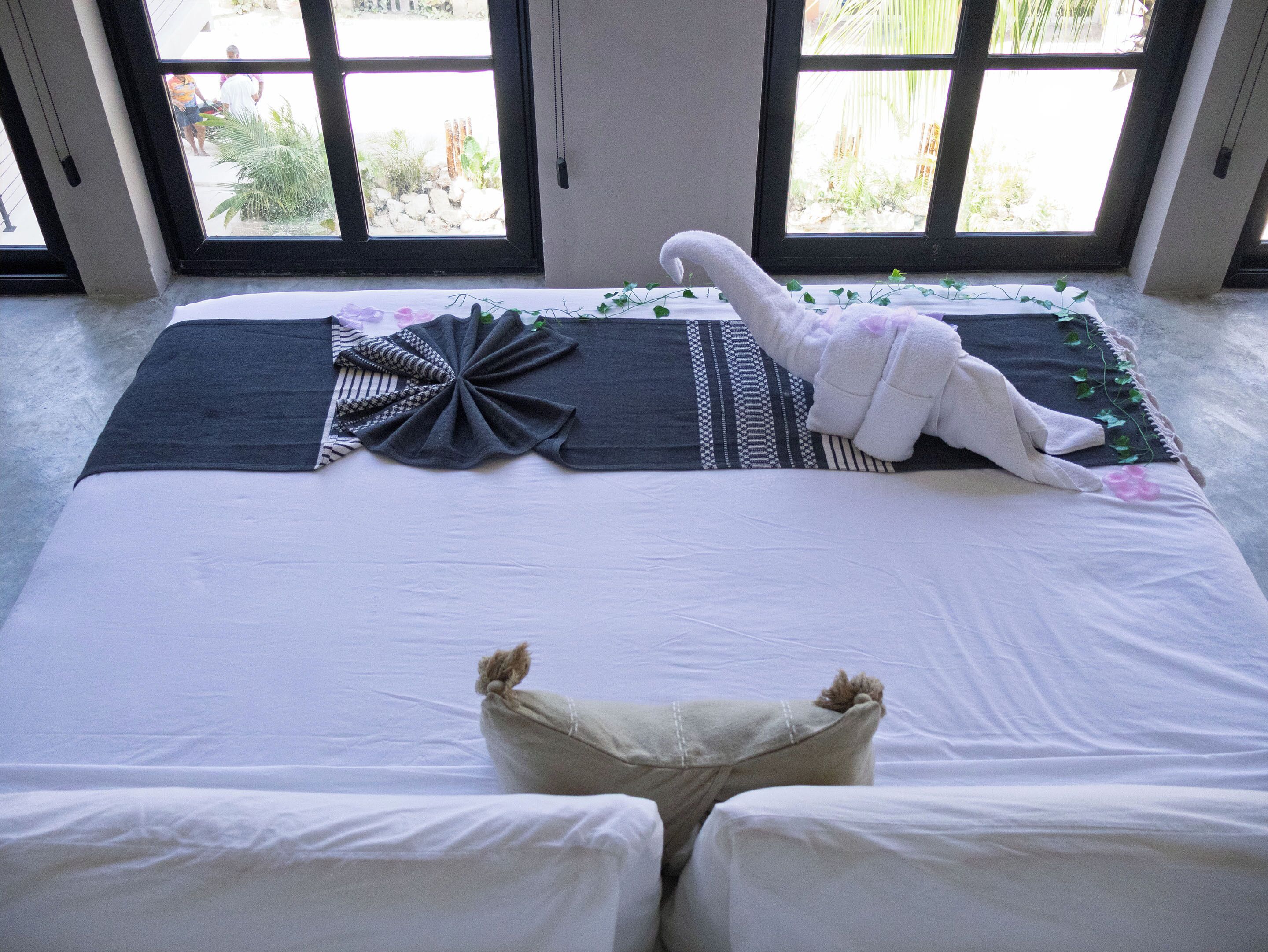 A bed with a white blanket, a decorative pillow, and a plush toy.