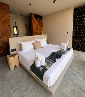 Una habitación de hotel moderna con una cama grande, cabecera de madera, mesita de noche y un panel decorativo en la pared.