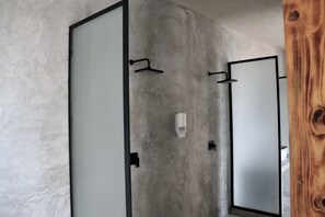 Un baño con pared de concreto, un marco de puerta de madera y un espejo.