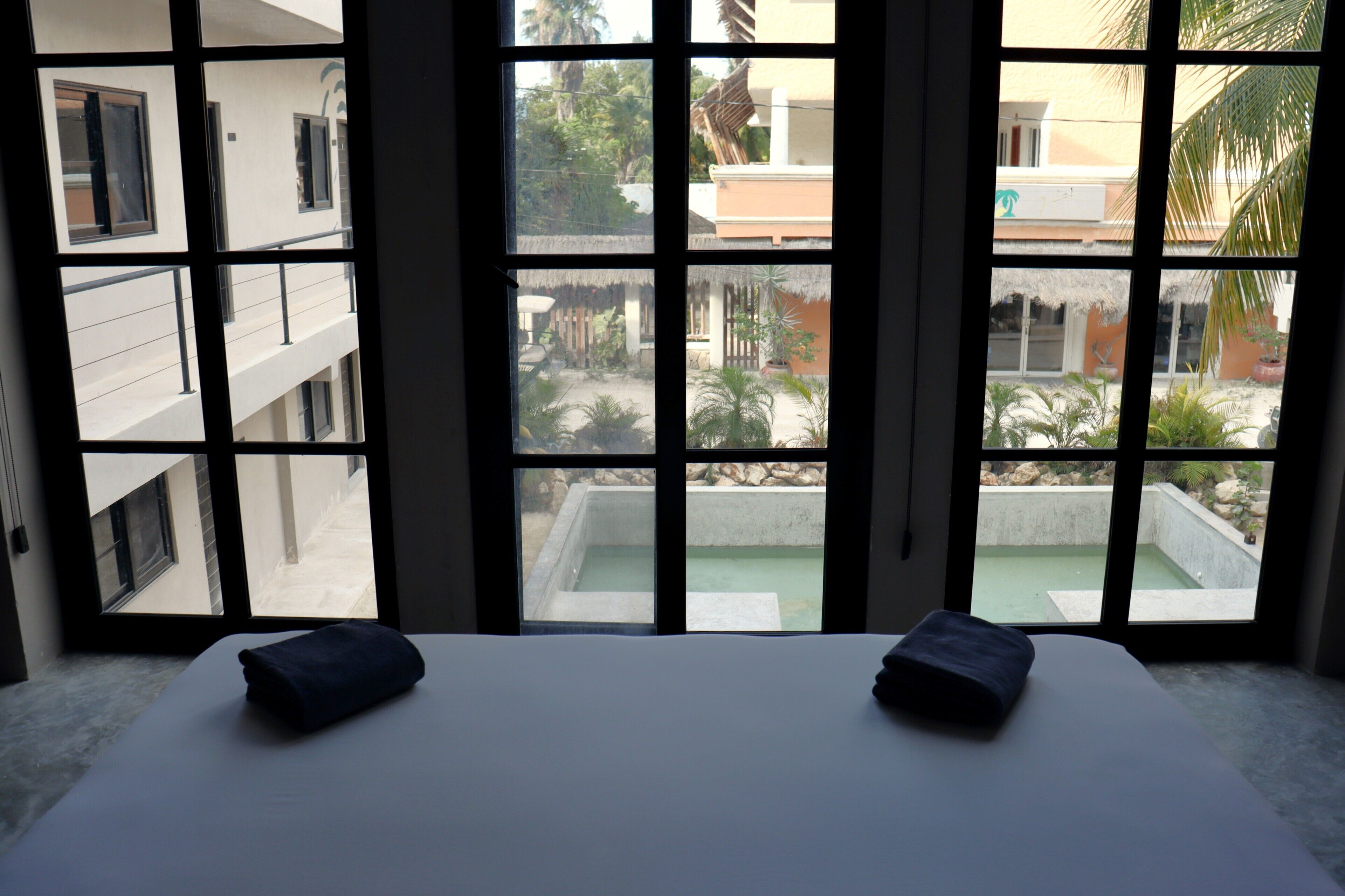Habitación con cama, dos almohadas y vistas amplias desde sus ventanas.