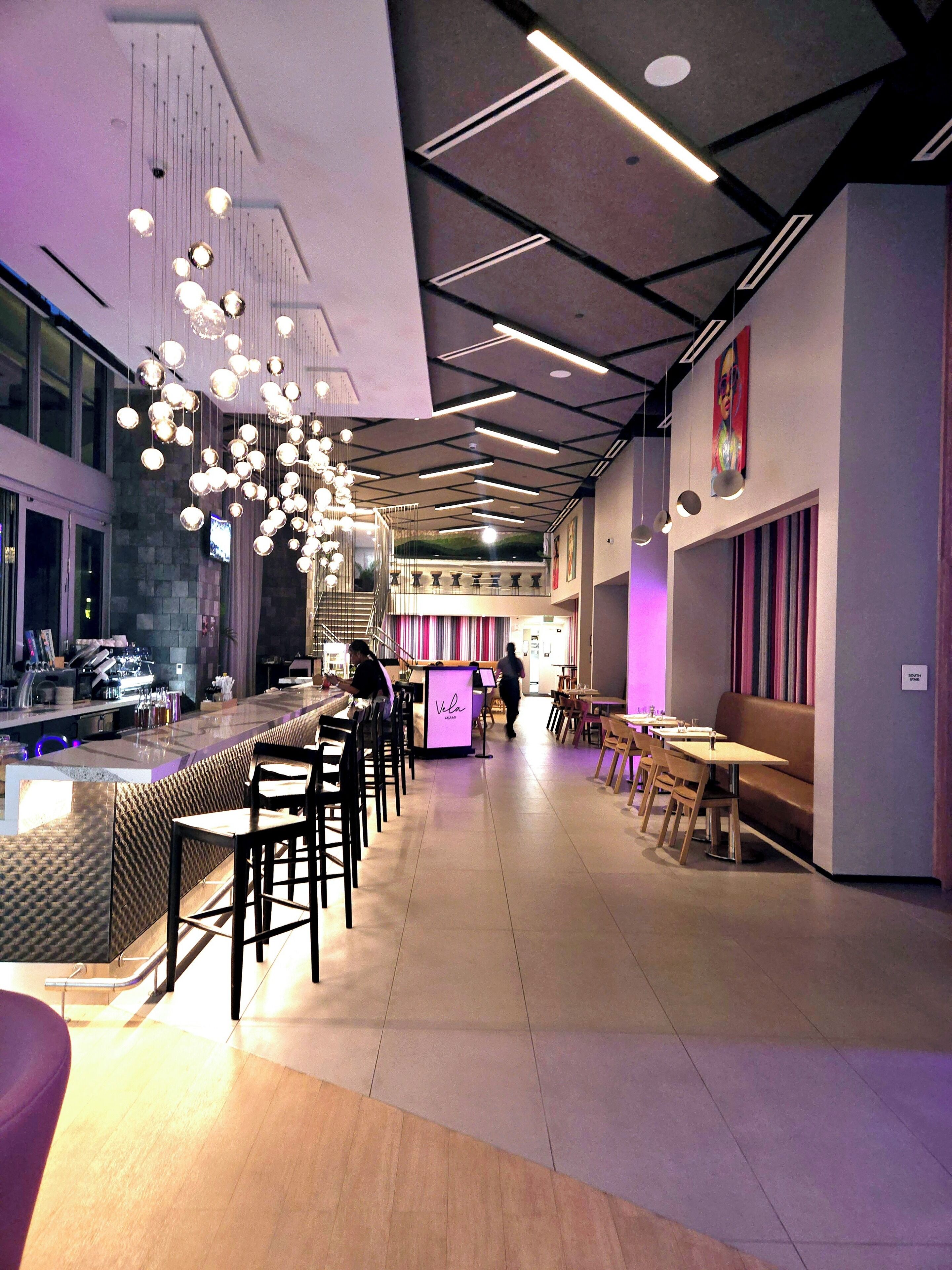 A modern bar area with a counter, bar stools, and hanging spherical light fixtures.