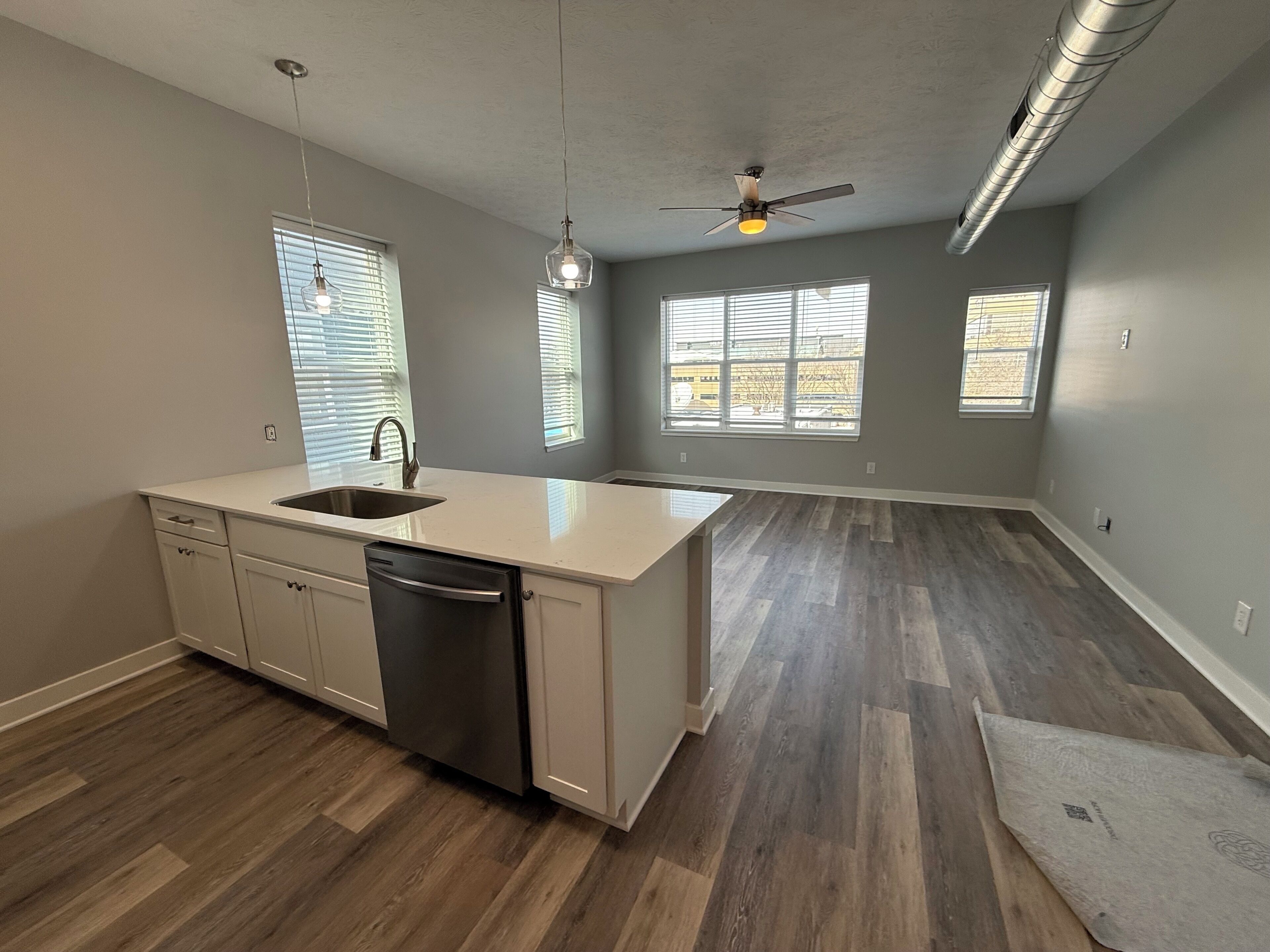 A kitchen with a dishwasher, a sink, and a ceiling fan.