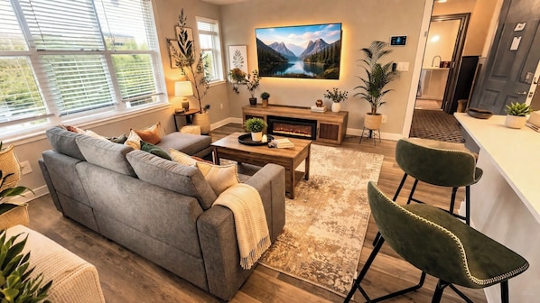 Una sala de estar moderna con sofá, mesa de centro y sillones, chimenea y televisor grande.