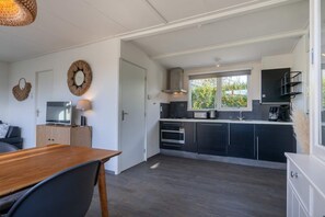 Eine kleine Küche mit dunklen Schränken, einem Holztisch und einem großen Fenster.