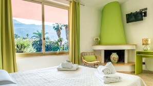 Una habitación de hotel con cama, sillón, chimenea y vistas al exterior.