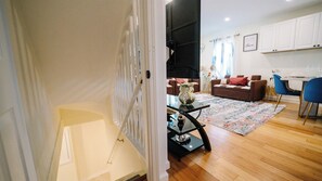 A living room with a sofa, a coffee table, and a dining area with a table and chairs. - 5BR Near DC Sleeps 20+ | Yard & Parking (Falls Church)