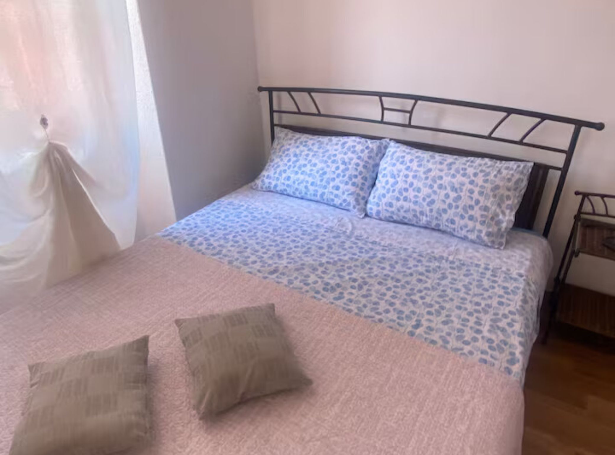 Un lit avec une couvre-lit à motifs, deux oreillers et une tête de lit en métal.