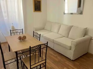 A room with a wooden dining table, two chairs, a white sofa, and a small painting on the wall. - Apartment old Town-novigrad 20 m From the sea (Novigrad)