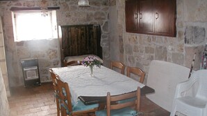 A dining area with a table, chairs, a cabinet, and a radiator. - Cottage 'La Laverie' with Shared Pool, Shared Garden and Wi-Fi (Allonnes)