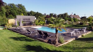 Un pati amb piscina, gandules i una palmera.