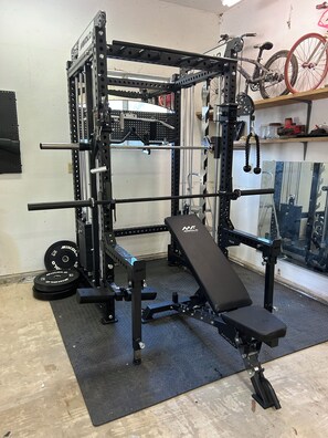 A gym with a squat rack, bench press, and weight plates. - Gorgeous 1-bedroom studio in charming Ojai (Ojai)
